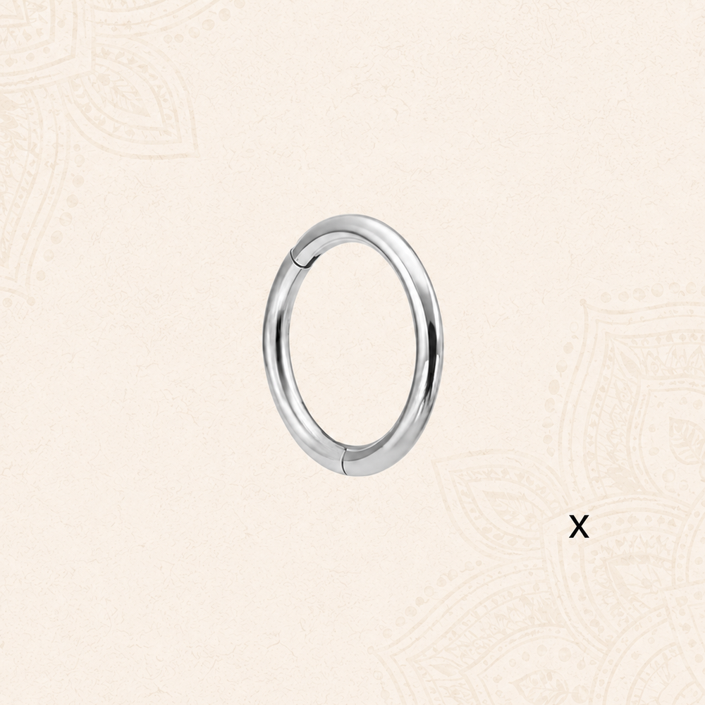 A polished silver-toned metal hoop NOSE RING on a light beige patterned background.
