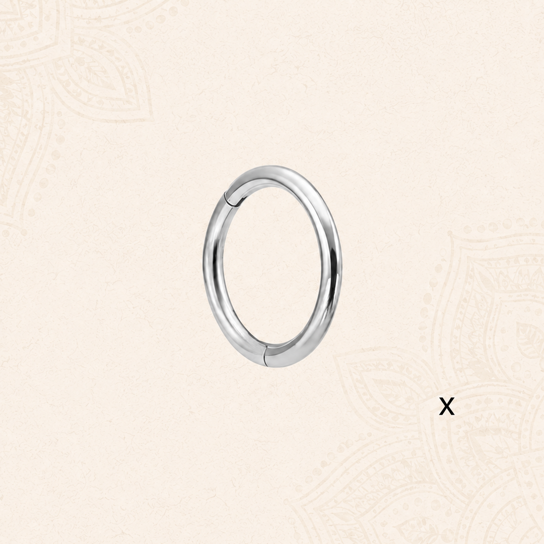 A polished silver-toned metal hoop NOSE RING on a light beige patterned background.