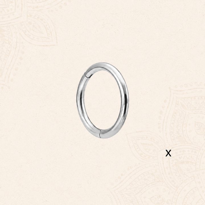 A polished silver-toned metal hoop NOSE RING on a light beige patterned background.