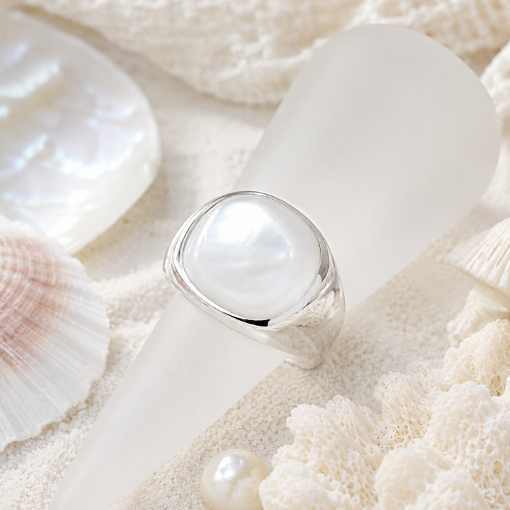 Mother of pearl statement ring in a sterling silver setting with a beach inspired background. 