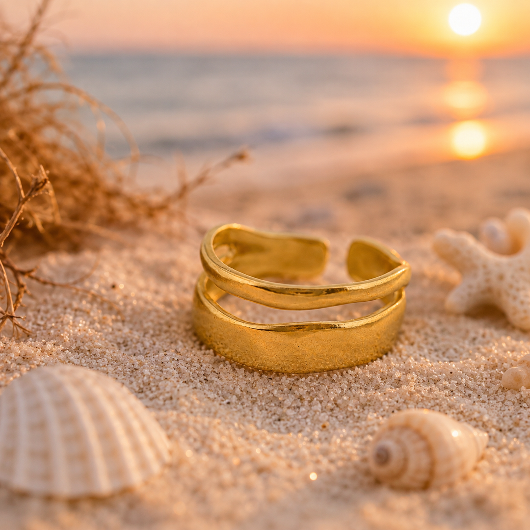 twin band Gold ring on sand with sunset and shells in background