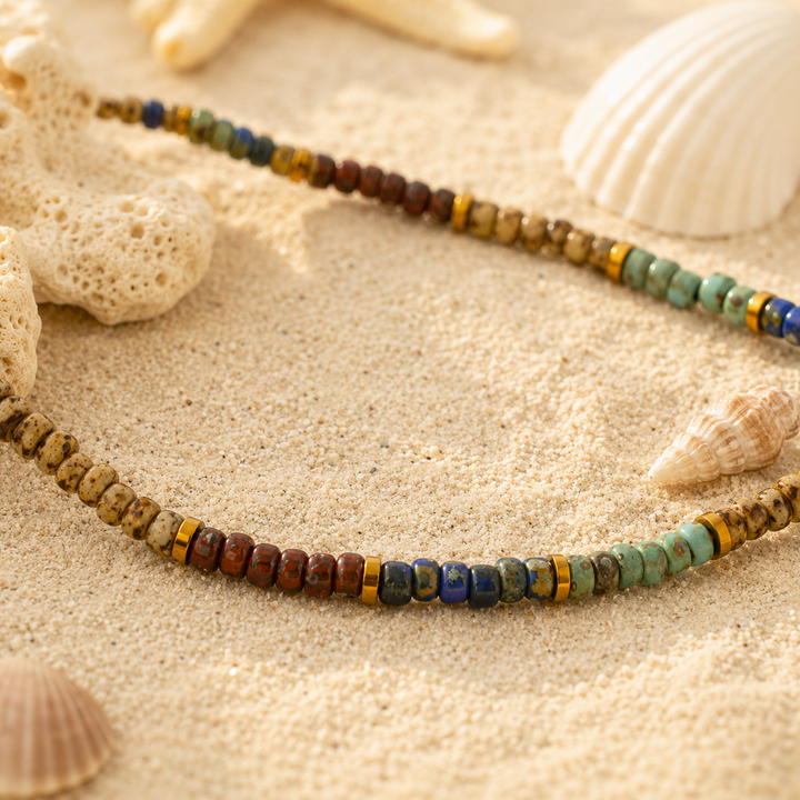 anklet with multicolored beads on a sandy surface with shells