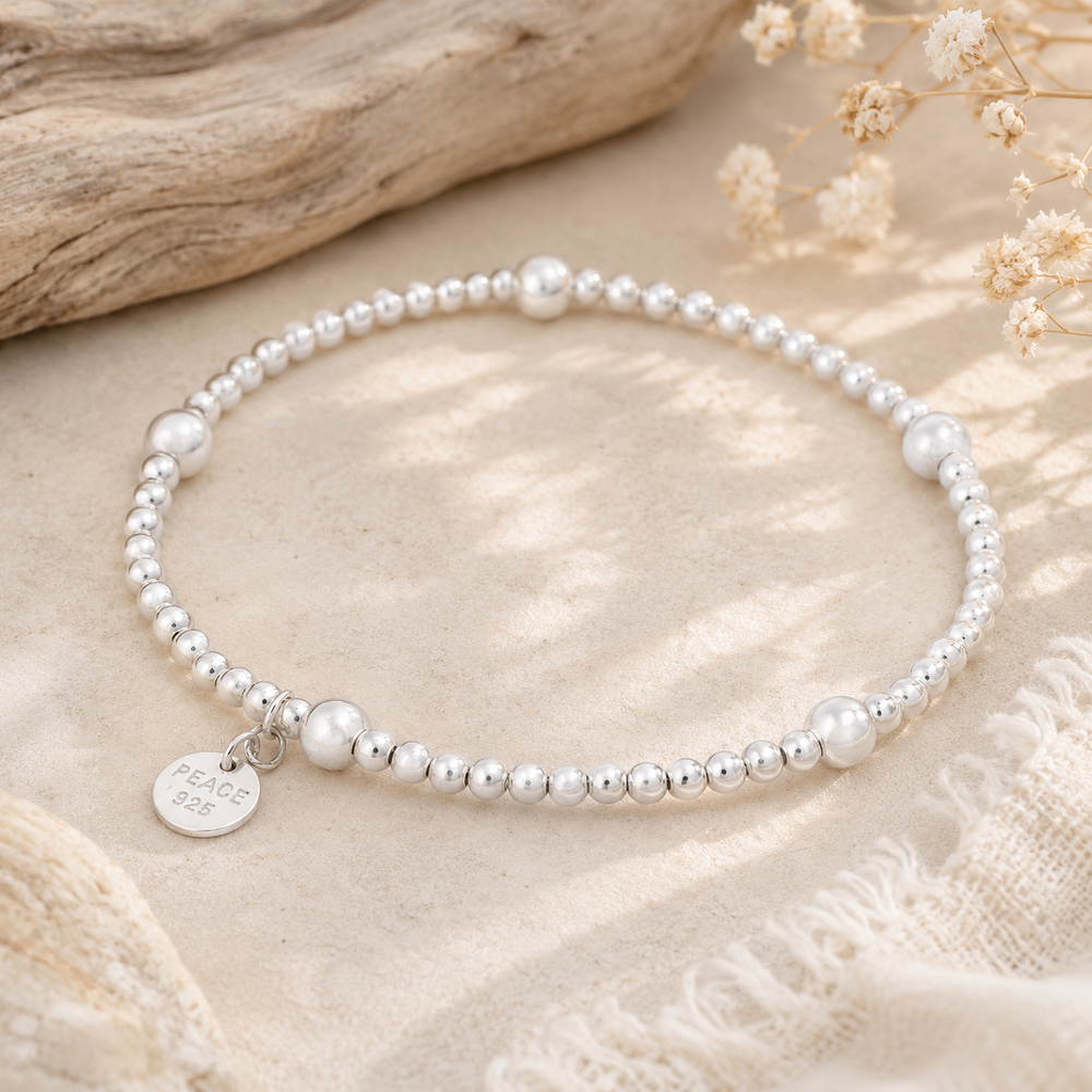 silver spiritual bracelet with a peace tag