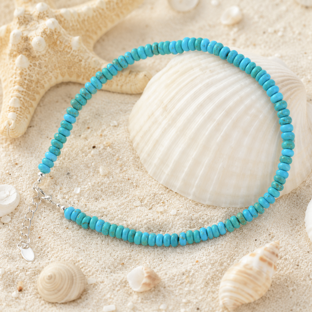 Turquoise beaded nanklet on a sandy surface with shells