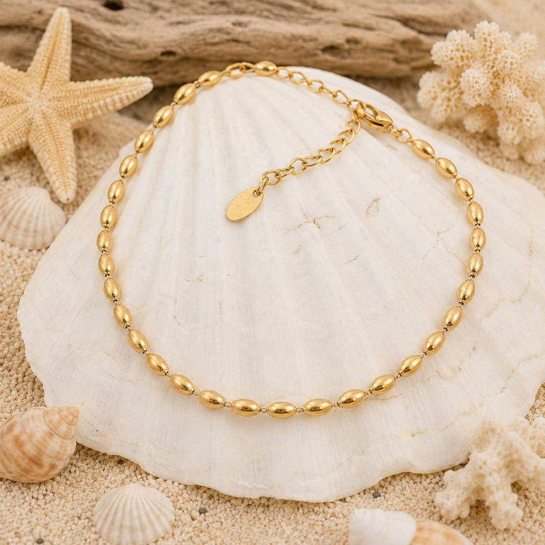Gold anklet on a white shell with beach elements