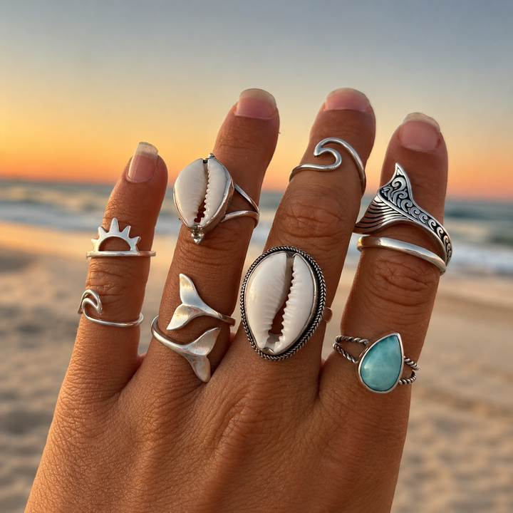 Hand wearing multiple sterling silver bohemian rings with a sunset beach background